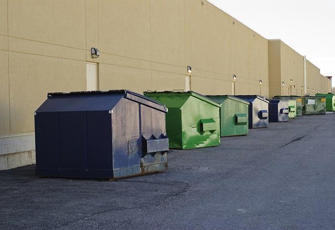 a construction worker empties a wheelbarrow of waste into the dumpster in Commack NY